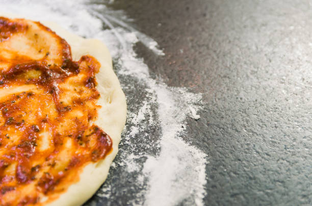 istock Preparing pizza, close-up of pizza dough with tomato sauce. 1005627364