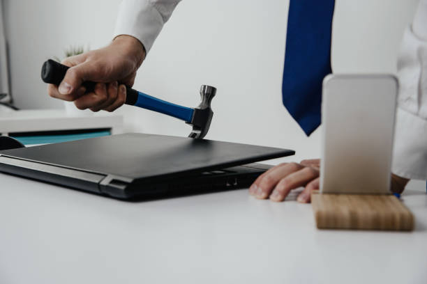 istock The man is trying to open a closed laptop using a hammer. 1005636886