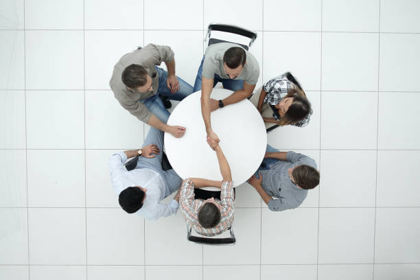 istock top view. handshake colleagues at the round table 1005644086