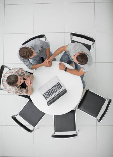 istock handshake of the colleagues sitting around the table 1005644434