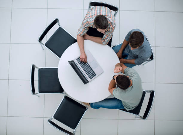 istock group of people with gadgets sitting at a round table 1005644452