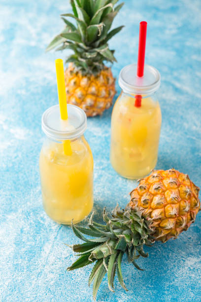 istock Fresh pineapple juice and ripe pineapple on grey background 1005656394