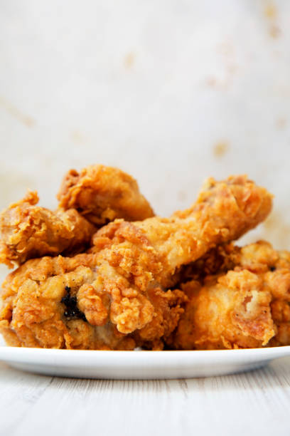 istock Fried chicken legs on a white round plate, closeup. Side view. 1005659106
