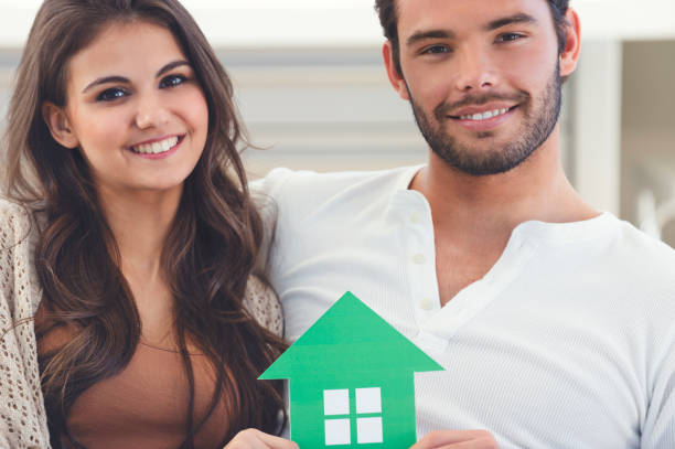 istock Couple holding a cardboard home icon. 1005667310