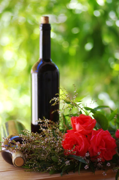 istock Roses with red wine bottles on wooden table 1005682894