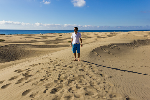 Lonely tourist on arid landscape with sea on the background in Canary Islands, Spain. Summer holidays, travel destination concepts