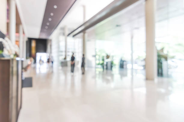 Hotel or office building lobby blur background interior view toward reception hall, modern luxury white room space with blurry corridor and building glass wall window