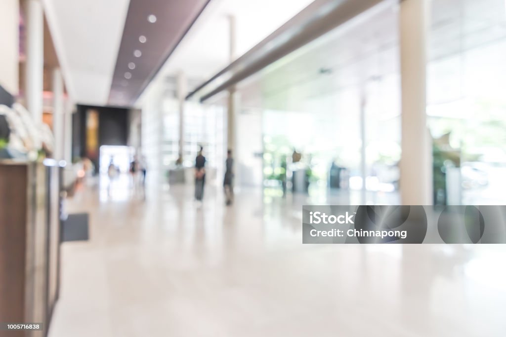 Hotel or office building lobby blur background interior view toward reception hall, modern luxury white room space with blurry corridor and building glass wall window Bank - Financial Building Stock Photo