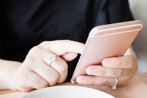 istock Woman with diamond ring on hand using smartphone in cafe restaurant 1005718062
