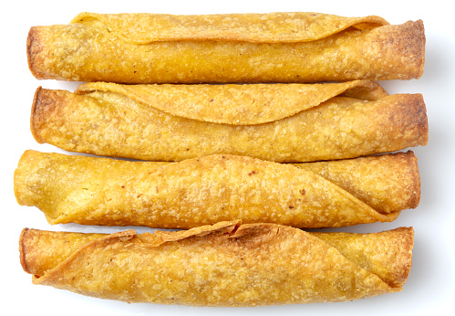 Four fried taquitos from above (mexican flautas) on white background