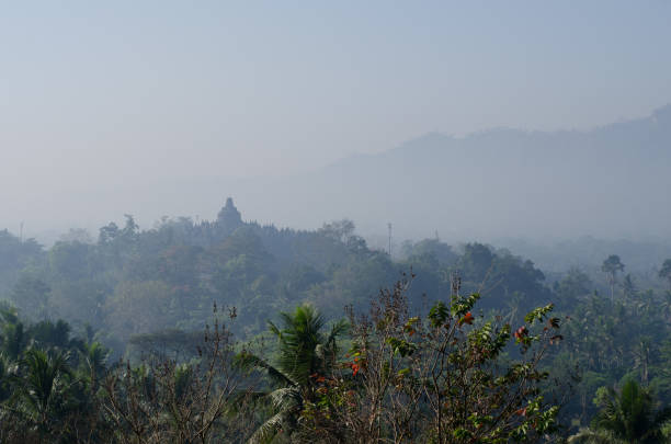 istock Borobudur temple and bell-enshrined Buddhas looking over the jungle and mountains of Java, Indonesia 1005766454
