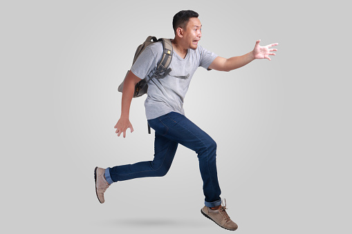 Attractive young Asian man worried and running fast to be late