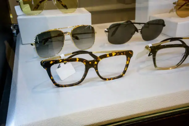 Photo of Various of colorful sun glasses in the shop display shelves. Selective focus