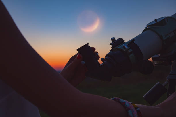 istock Girl looking at lunar eclipse through a telescope. My astronomy work. 1005801022
