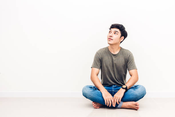 istock Handsome man sitting relax on floor against copy space for adding text with white wall background 1005833564