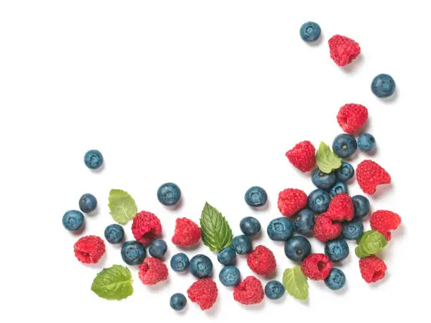 Various fresh summer berries background with copy space for text.Creative layout of fresh blueberries, raspberries and mint leaves, isolated on white background with clipping path.Top view or flat lay