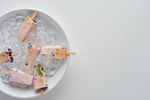 top view of delicious homemade fruity popsicles with ice cubes on grey