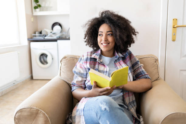 istock African woman sitting at home with a book 1005846582