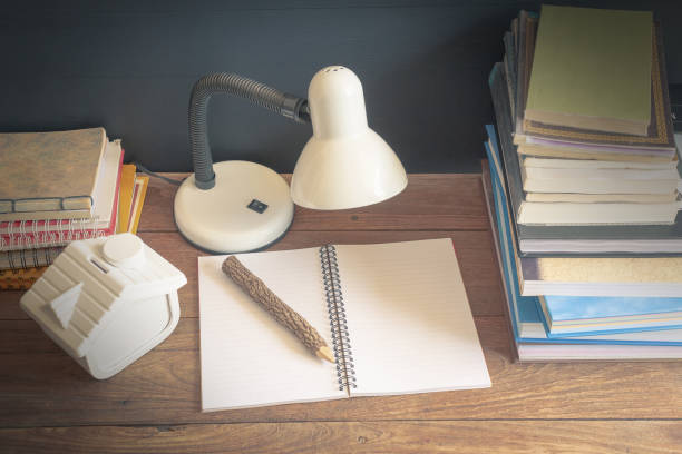 istock Workplace with reading lamp and books on old wooden table. vintage concept 1005853570
