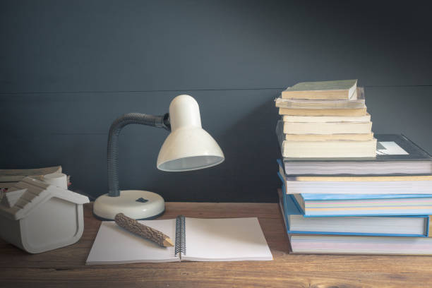 istock Workplace with reading lamp and books on old wooden table. vintage concept 1005853576