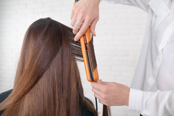 istock Hairstylist working with client's brown hair. 1005853758