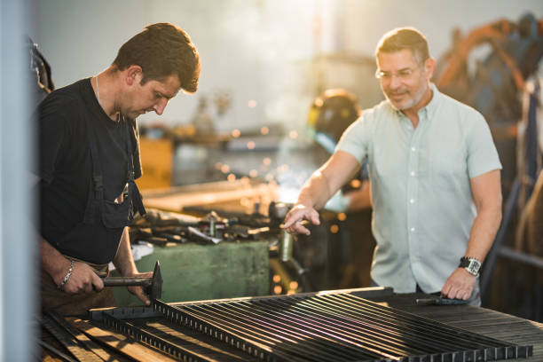 istock Steel worker hammering iron while his manager is giving him instructions in aluminum mill. 1005853966