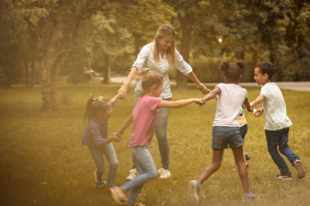 istock Group of little friends playing with teacher. 1005854062