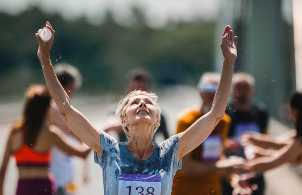 istock Senior marathon runner refreshing herself with water during a race. 1005860328