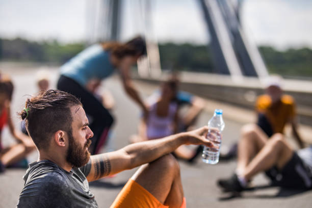 istock Young exhausted athlete taking a water break from marathon race. 1005860430