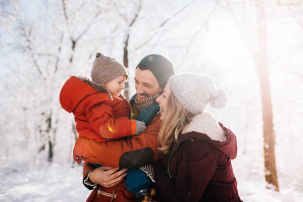 Winter family portrait Photo of a cheerful young family, being playful outdoors in nature covered in snow family christmas stock pictures, royalty-free photos & images