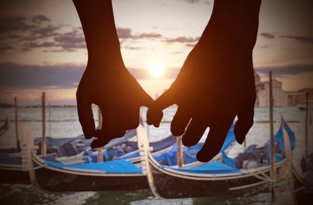Touching hands of lovers in Venice during sunset.