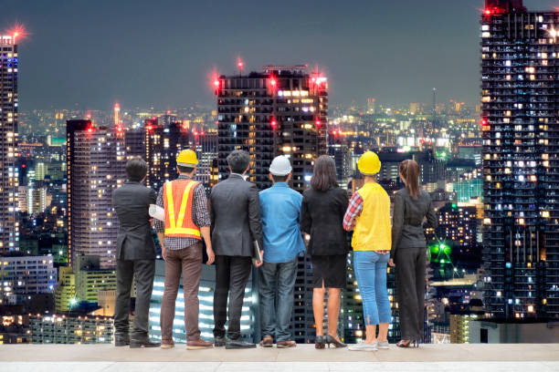 istock Team international business people with engineer professional standing on skyscraper tower of light in urban 1005871230