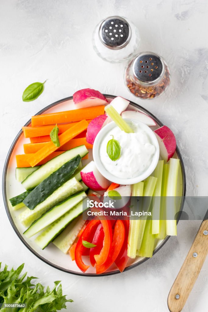 Vegetable sticks of cucumber, pepper, carrots, celery and radishes with white sauce of sour cream, yogurt, herbs. Tasty vegetable sticks of cucumber, pepper, carrots, celery and radishes with white sauce of sour cream, yogurt, herbs. Dipping Sauce Stock Photo