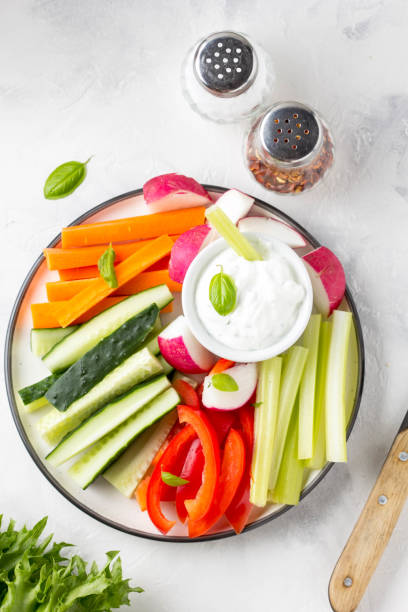 Vegetable sticks of cucumber, pepper, carrots, celery and radishes with white sauce of sour cream, yogurt, herbs. stock photo