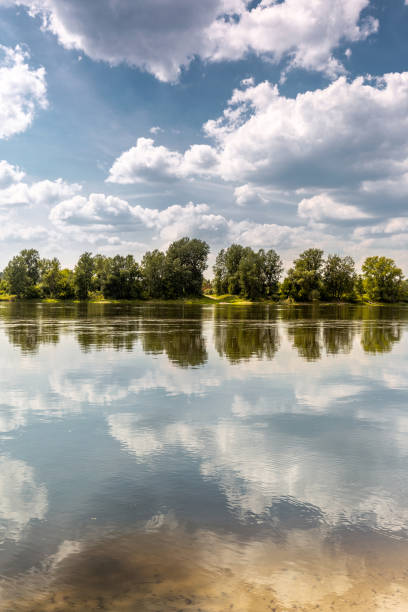 Lazy summer day at river bank. Line of trees at oposite bank makes symmetry