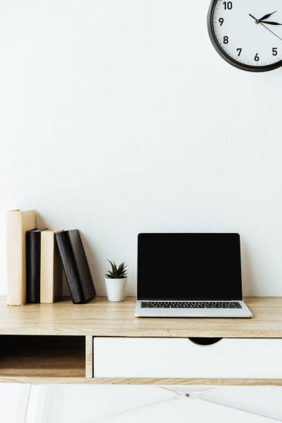istock laptop with blank screen and books on work desk in front of white wall 1005882708