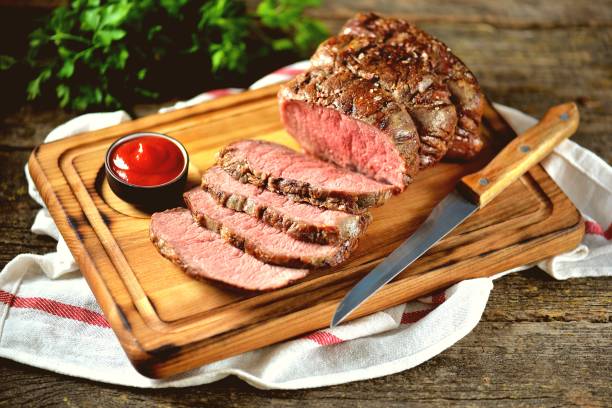 istock Roast beef medium on a wooden board. Rustic style. 1005889472