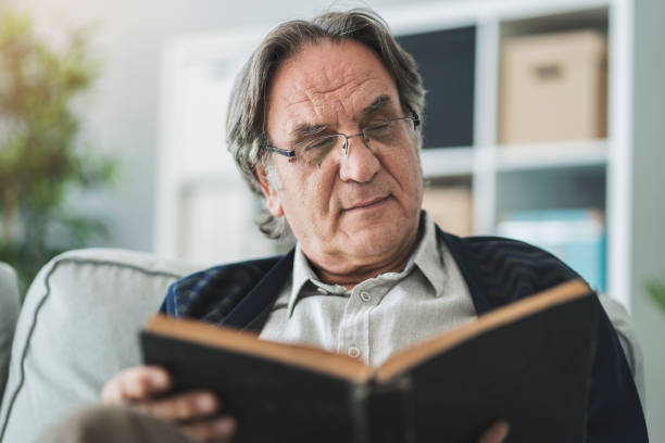 istock Old man reading book at home 1005889578