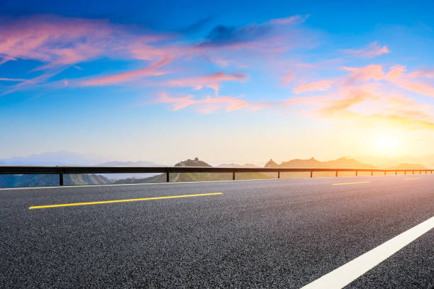 istock Asphalt road and great wall with mountains at sunset 1005889600