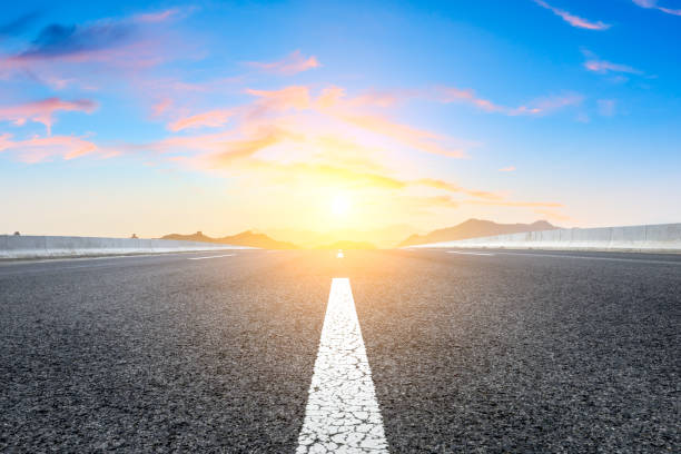 istock Asphalt road and great wall with mountains at sunset 1005889864