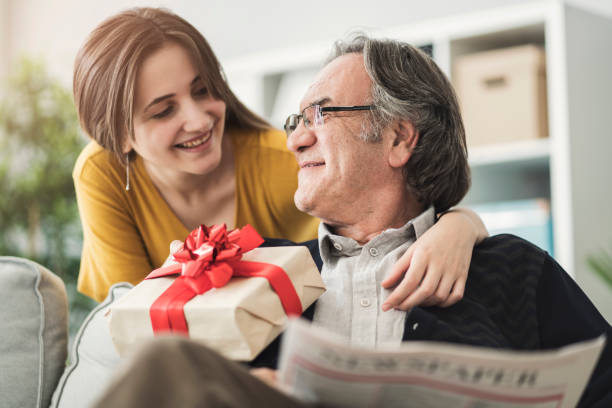 young woman giving gift her father - senior adult with daughter father imagens e fotografias de stock