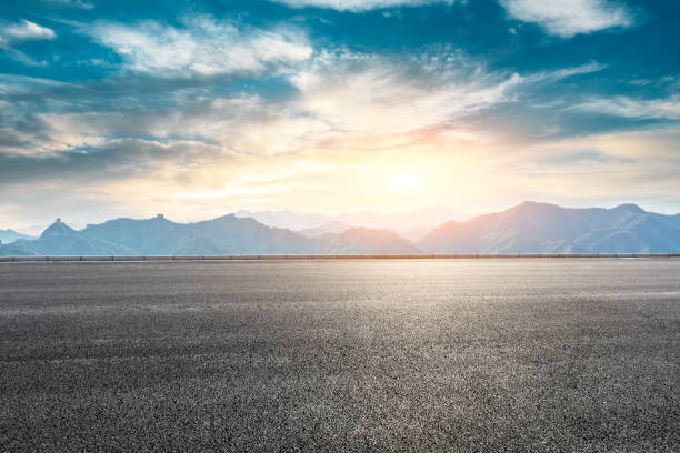 istock Asphalt road and great wall with mountains at sunset 1005890848