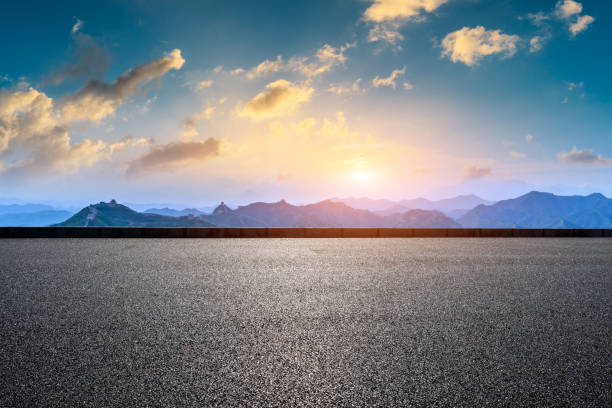 istock Asphalt road and great wall with mountains at sunset 1005893540