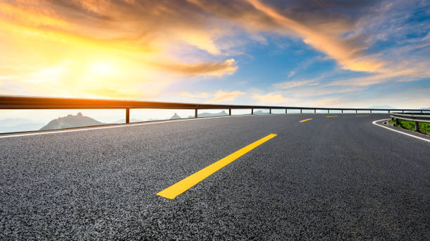 istock Asphalt road and great wall with mountains at sunset 1005893546