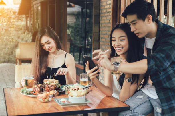 Asian single woman envious with love couple doing take selfie at restaurant. Asian single woman envious with love couple doing take selfie at restaurant. jealous ex girlfriend stock pictures, royalty-free photos & images