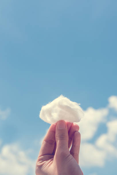 istock Woman hand holding cotton wool on cloud sky background. 1005896770