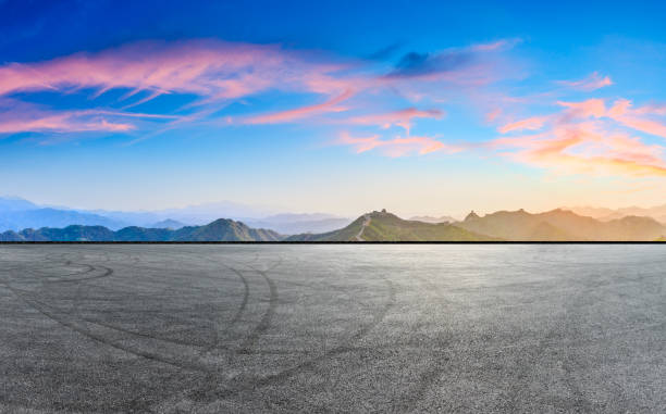 istock Asphalt road and great wall with mountains at sunset 1005897132