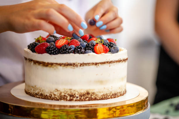 istock Girl chef cooks confectioner, decorates cake with forest berries. concept making without lactose cakes. Copy space, selective focus 1005897706