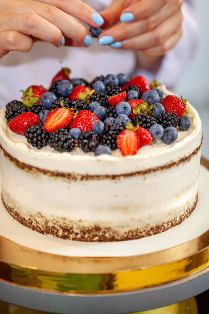 istock Girl chef cooks confectioner, decorates cake with forest berries. concept making without lactose cakes. Copy space, selective focus 1005897710