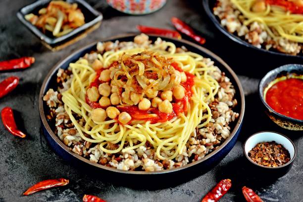 istock Kushari or Koushari - Egyptian dish of lentils, rice, pasta, chickpeas with tomato sauce and crispy onions. Arabic cuisine 1005905708